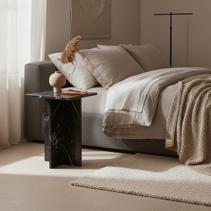 Table de chevet en marbre véritable à côté d'un lit avec du linge de maison en lin naturel.