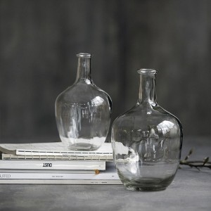 Deux vases bouteille en verre transparent de tailles différentes posés sur des livres, fond gris - House Doctor - Woodely