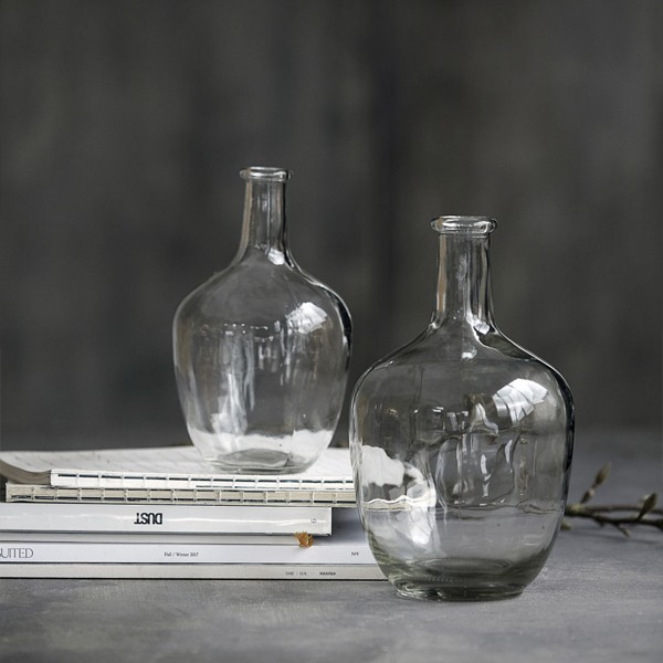 Deux vases bouteille en verre transparent de tailles différentes posés sur des livres, fond gris - House Doctor - Woodely